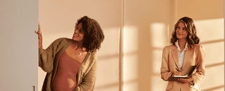 Mulher admirando o condominio ao lado da vendedora