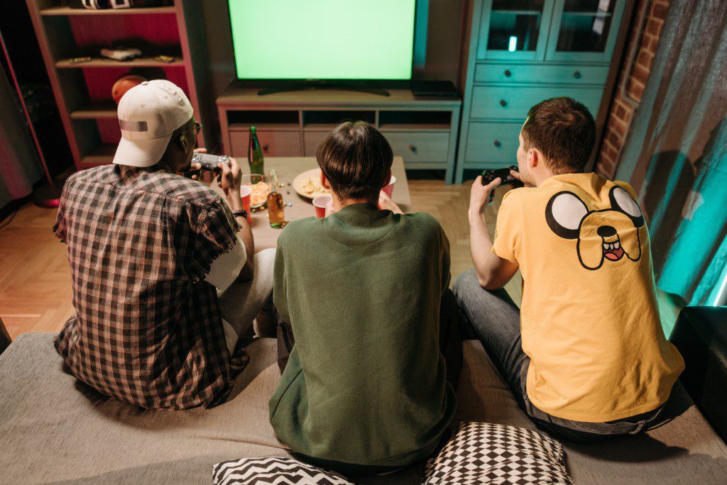 Foto que ilustra matéria sobre receber amigos em casa mostra três jovens jogando videogame