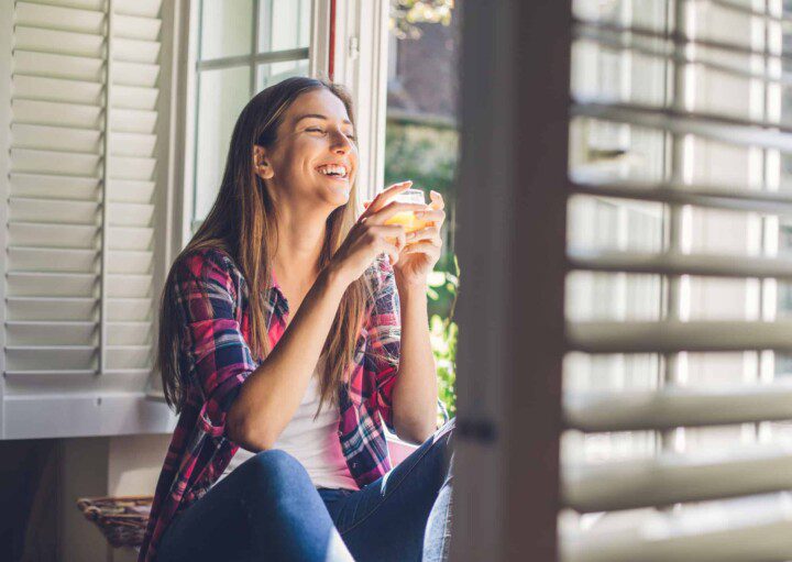 Viver sem ar condicionado - Mulher aproveita ar fresco que entra pela janela de casa