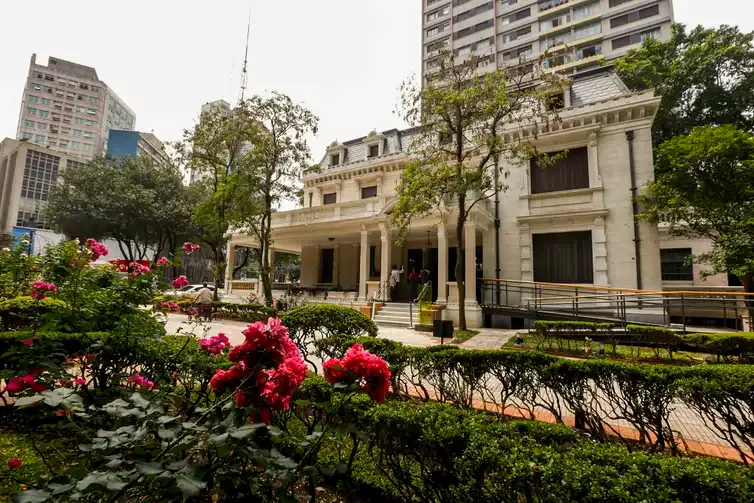 Imagem da Casa das Rosas, uma histórica mansão branca com colunas e detalhes ornamentados na Avenida Paulista.