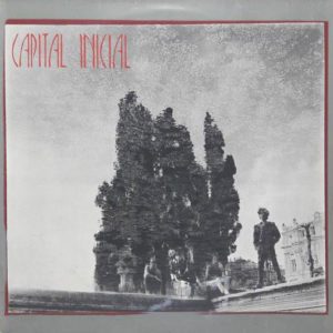 Capa de &aacute;lbum em preto e branco com &aacute;rvores altas e quatro pessoas em p&eacute; ou sentadas perto delas. INICIAL MAI&Uacute;SCULA est&aacute; escrito em letras vermelhas estilizadas no canto superior esquerdo. Um pouco de arquitetura &eacute; vis&iacute;vel ao fundo.