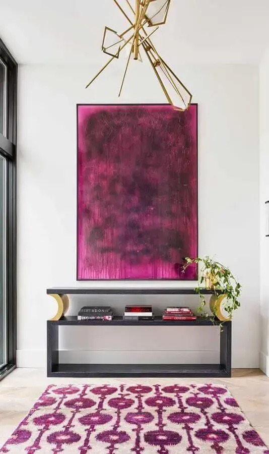 Imagem de um hall de entrada com quadro, aparador e tapete. 