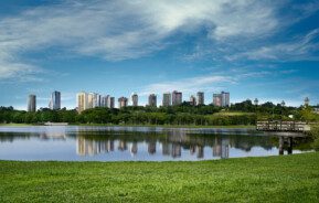 Foto que ilustra matéria sobre os bairros mais seguros de Curitiba mostra um lago do Parque Barigui com prédios altos ao fundo.