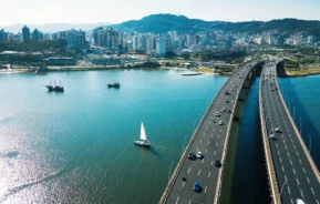 Imagem aérea da Ilha de Santa Catarina durante um dia ensolorado para ilustrar matéria sobre os melhores bairros de Florianópolis