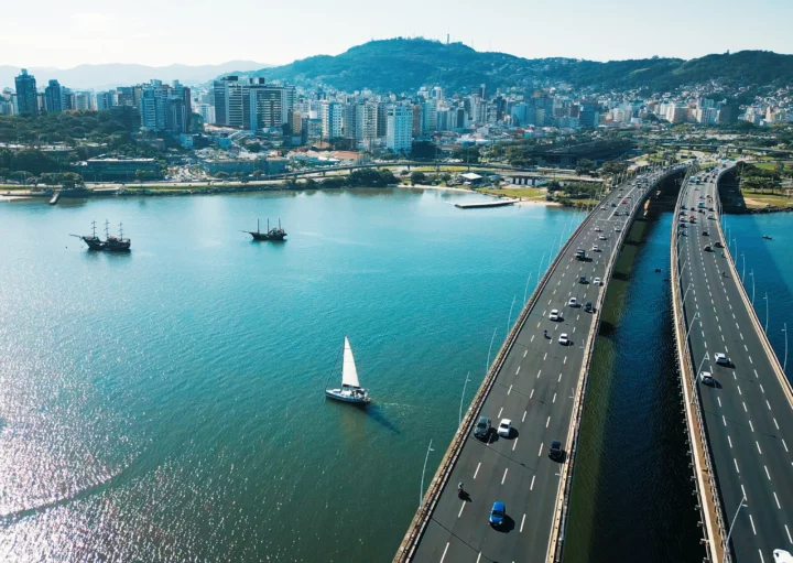 Imagem aérea da Ilha de Santa Catarina durante um dia ensolorado para ilustrar matéria sobre os melhores bairros de Florianópolis