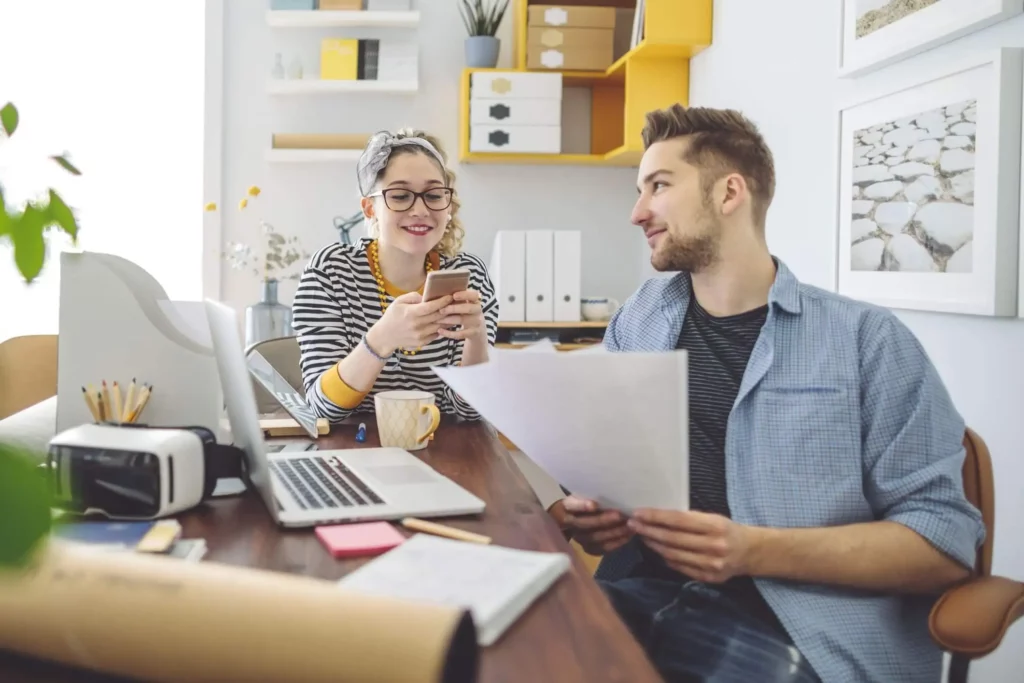 Imagem de um casal formado por um homem e uma mulher trabalhando ao redor de uma mesa onde estão papéis, um notebook, uma xícara de café e outros itens de escritório para ilustrar matéria sobre se vale a pena financiar apartamento na planta