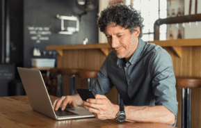 Homem sentado à mesa pesquisando sobre a lei do inquilinato no computador.