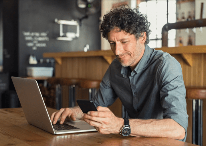 Homem sentado à mesa pesquisando sobre a lei do inquilinato no computador.