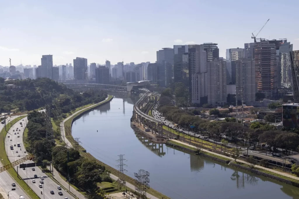 Imagem da Marginal Pinheiros e do Rio Pinheiros, em São Paulo, e prédios ao redor em um dia parcialmente nublado
