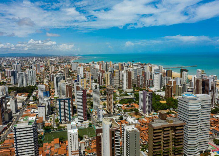 Foto que ilustra matéria sobre o custo de vida em Fortaleza mostra os prédios da cidade com o mar azul ao fundo.