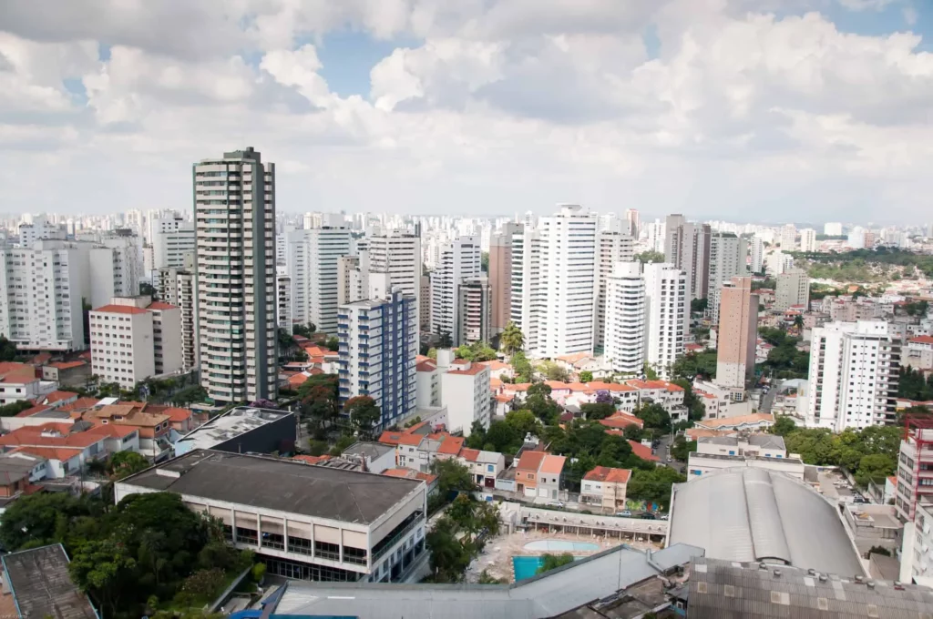 Imagem da vista aérea da Vila Mariana, em São Paulo, mostra prédios altos de apartamentos e arranha-céus misturados com casas menores e árvores verdes sob um céu parcialmente nublado para ilustrar matéria sobre qual o bairro mais seguro de São Paulo