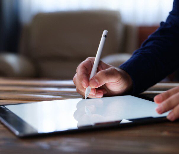 Foto que ilustra matéria sobre tipos de financiamento imobiliário mostra a mão de um homem assinando um contrato digital em um tablet.