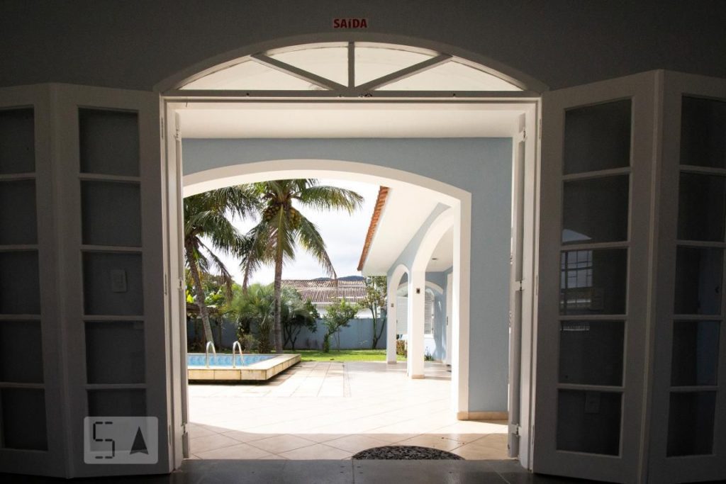 Vista da piscina pelo lado de dentro da casa. Porta dupla para a varanda.