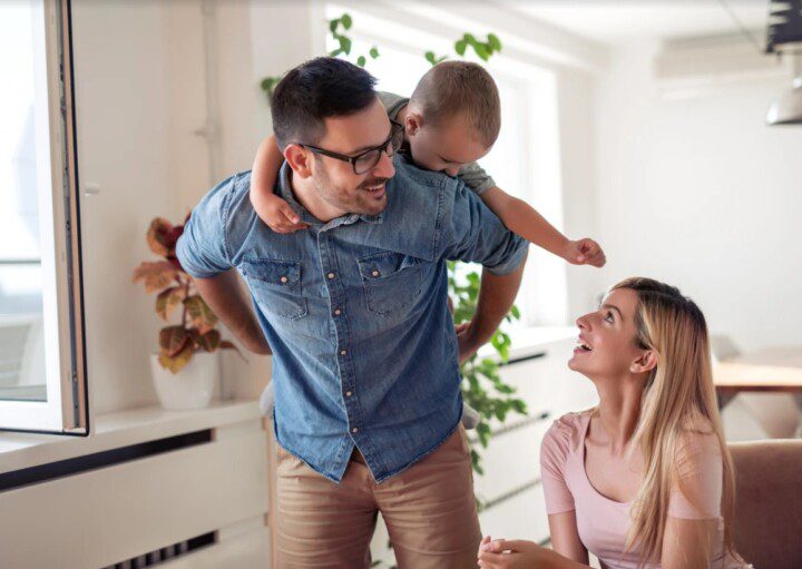 Casal na cozinha da casa de condomínio brincando com o bebê