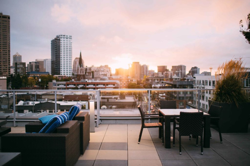 terraço de uma cobertura, com mesas e cadeiras e sofás e vista para a cidade