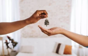 Imagem de um agente imobiliário entregando a uma pessoa as chaves da sua nova casa para ilustrar matéria sobre como funciona o seguro fiança