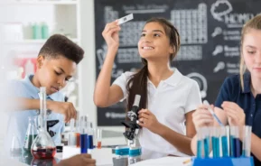 Imagem de três estudantes fazendo um projeto de ciências no laboratório com microscópio e lâmina de estudos para ilustrar matéria sobre as escolas particulares do Rio de Janeiro