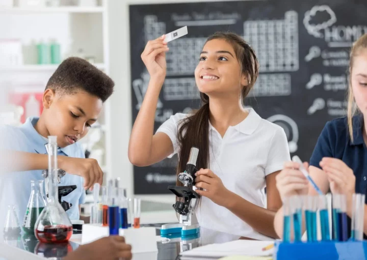 Imagem de três estudantes fazendo um projeto de ciências no laboratório com microscópio e lâmina de estudos para ilustrar matéria sobre as escolas particulares do Rio de Janeiro
