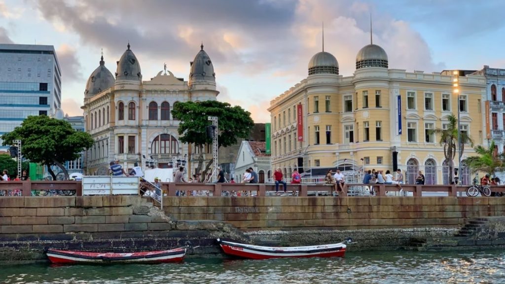 Vista de dois barquinhos às margens da praia, com a cidade ao fundo, em Recife PE