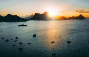 imagem da praia de São Francisco, em Niterói, mostra barcos na água e montanhas ao fundo