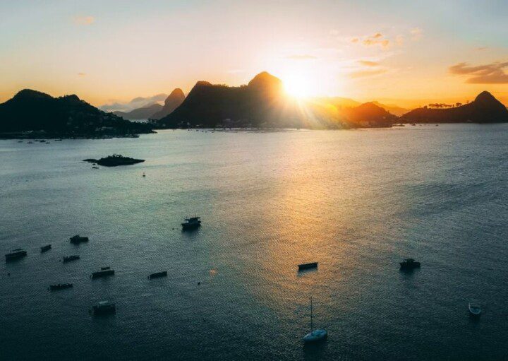 imagem da praia de São Francisco, em Niterói, mostra barcos na água e montanhas ao fundo