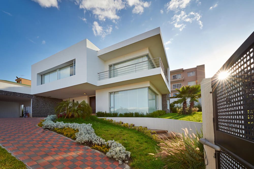 Exemplo de casa quadrada branca, com dois andares e amplas janelas. A casa tem um formato bem geométrico.