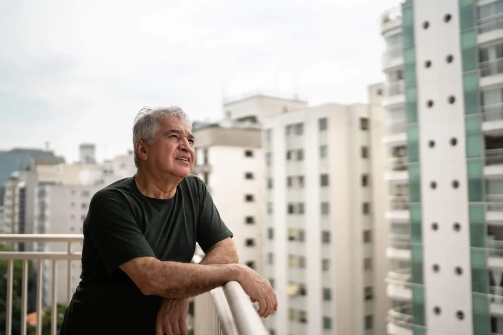 Imagem de um senhor idoso na sacada de um apartamento olhando a vista da cidade para ilustrar matéria sobre onde fica a Zona Norte de São Paulo