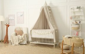 Foto que ilustra matéria sobre quarto de bebê unissex mostra um quarto com um berço branco no centro, uma poltrona de amamentação à esquerda do berço e algumas prateleiras com enfeites do lado direito.