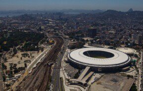 Foto que ilustra matéria sobre a Zona Norte do RJ mostra uma visão do alto do Maracanã, que aparece mais à direita da tela, com a linha do trem à esquerda e, ao fundo, o resto da cidade, com toda a região Central, a Baía de Guanabara e as montanhas ao fundo.