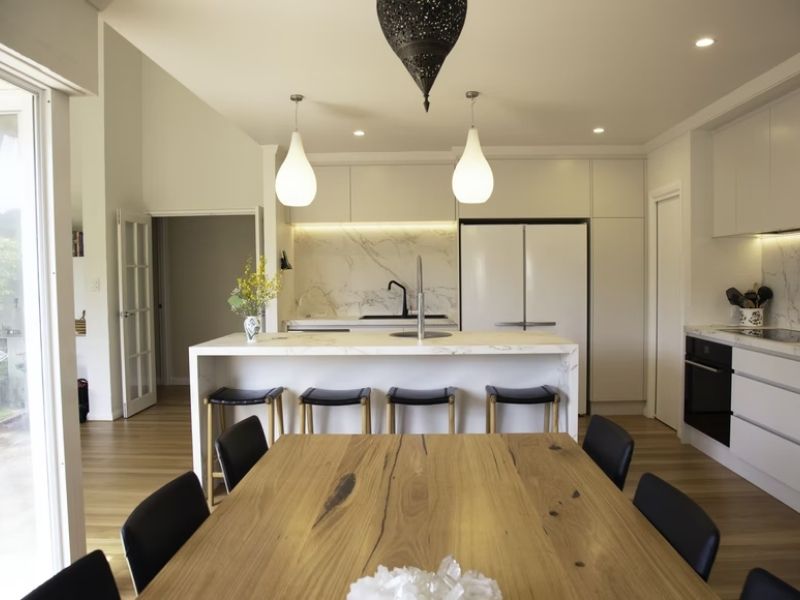 cozinha americana, ao fundo com a geladeira e armários, na frente com a mesa e cadeiras