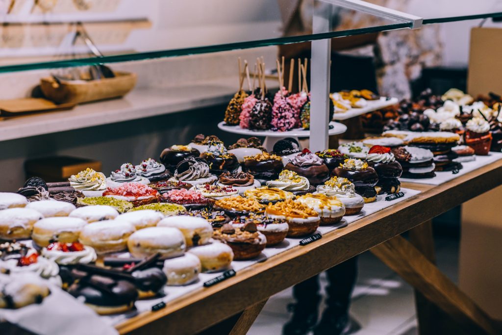 Exemplo de mesa de doces para decoração de chá de panela com cupcakes e outros docinhos à mostra em cima de uma mesa de madeira