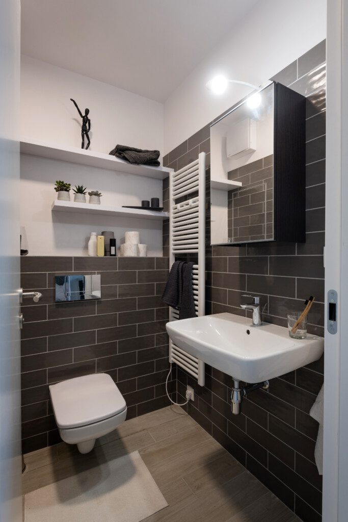 Lavabo preto e branco com parede de tijolinhos. 