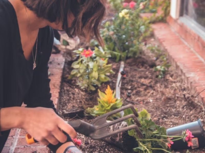 mulher com item de jardinagem mexendo na terra florida