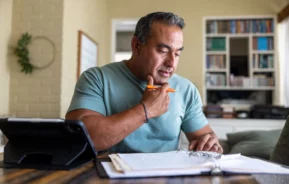 imagem que ilustra matéria sobre imposto de renda 2025 mostra um homem sentando e lendo papéis à sua frente com cara de reflexivo