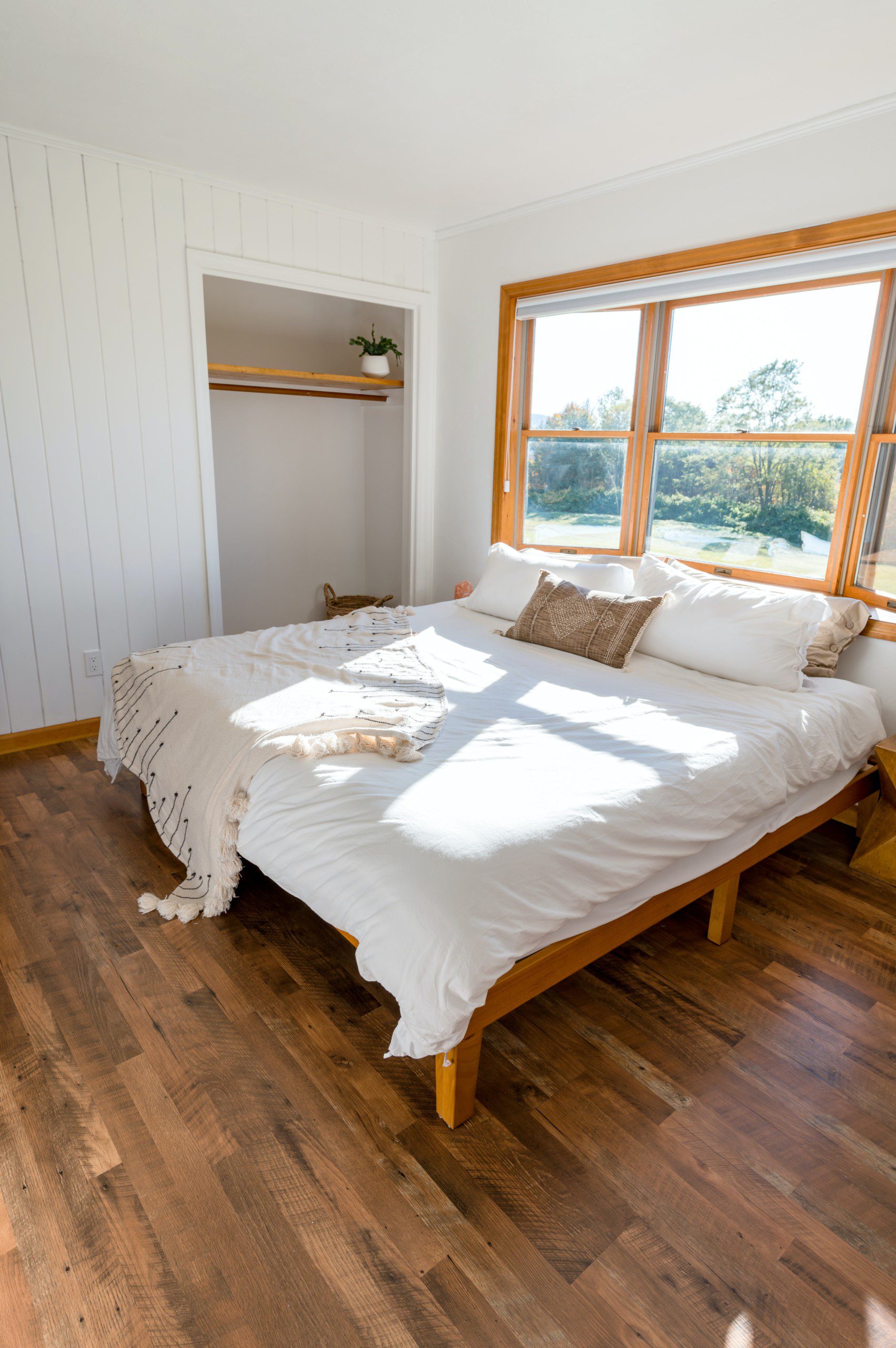 Imagem de uma cama de casal com decoração estilo boho em tons terrosos e branco com uma manta peseira.