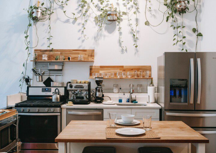 Imagem de uma cozinha organizada com utensílios, plantas pendentes e muita madeira.