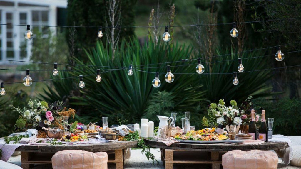 luzes penduradas sobre mesa de jantar posta para decoração de noivado