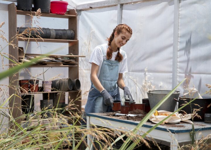 Imagem de uma mulher ruiva com avental, preparando uma composteira doméstica.