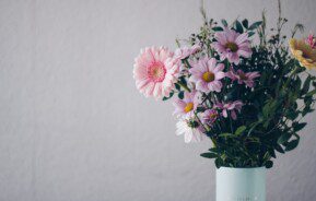 Imagem de um vaso azul claro com um arranjo de flores coloridas.