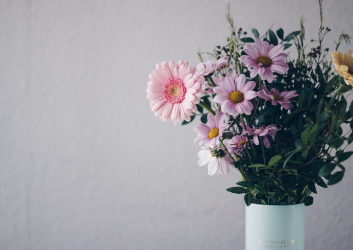 Imagem de um vaso azul claro com um arranjo de flores coloridas.