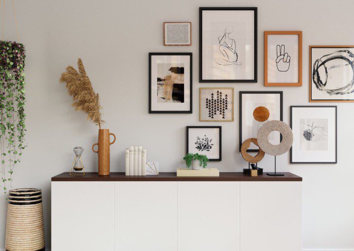 Sala de estar de casa, em tons neutros, com aparador branco. Acima do móvel, itens de decoração, como vasos e plantas. Quadros coloridos pendurados na parede