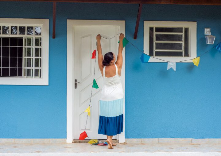 Imagem de uma mulher pendurando bandeirinhas de festa junina.