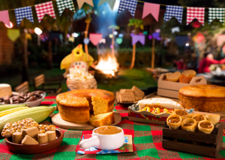 comidas típicas de festa junina e bandeirinhas ao fundo