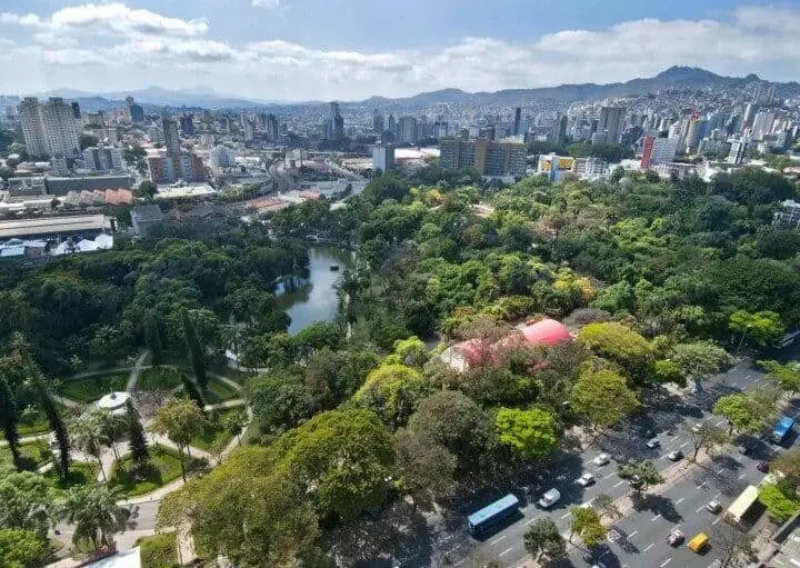 Imagem da vista aérea de um parque em Belo Horizonte mostra vegetação, lago, avenidas, automóveis circulando pela cidade e prédios ao fundo para ilustrar matéria sobre o melhor bairro de Belo Horizonte