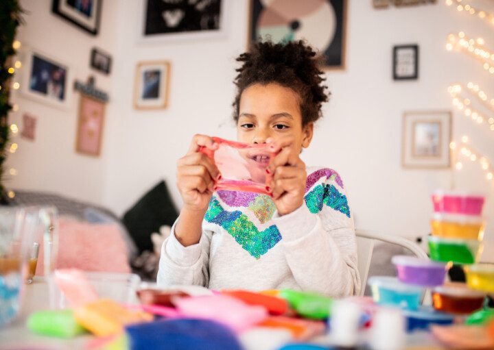 Imagem de uma menina brincando com slime.