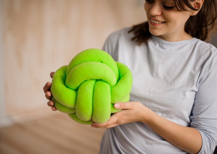 Imagem de uma mulher segurando uma almofada de nó verde.