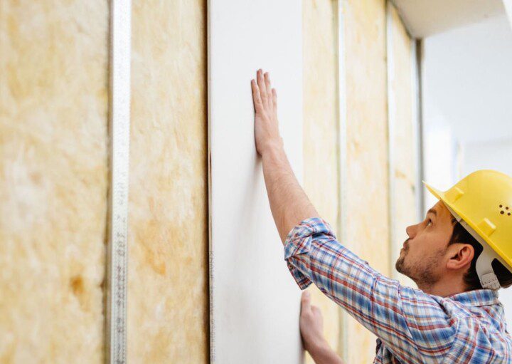 Imagem de um homem fazendo a instalação de uma parede de gesso.