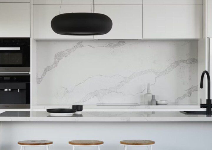 parede de pedra, bancada e armário suspenso em cozinha moderna