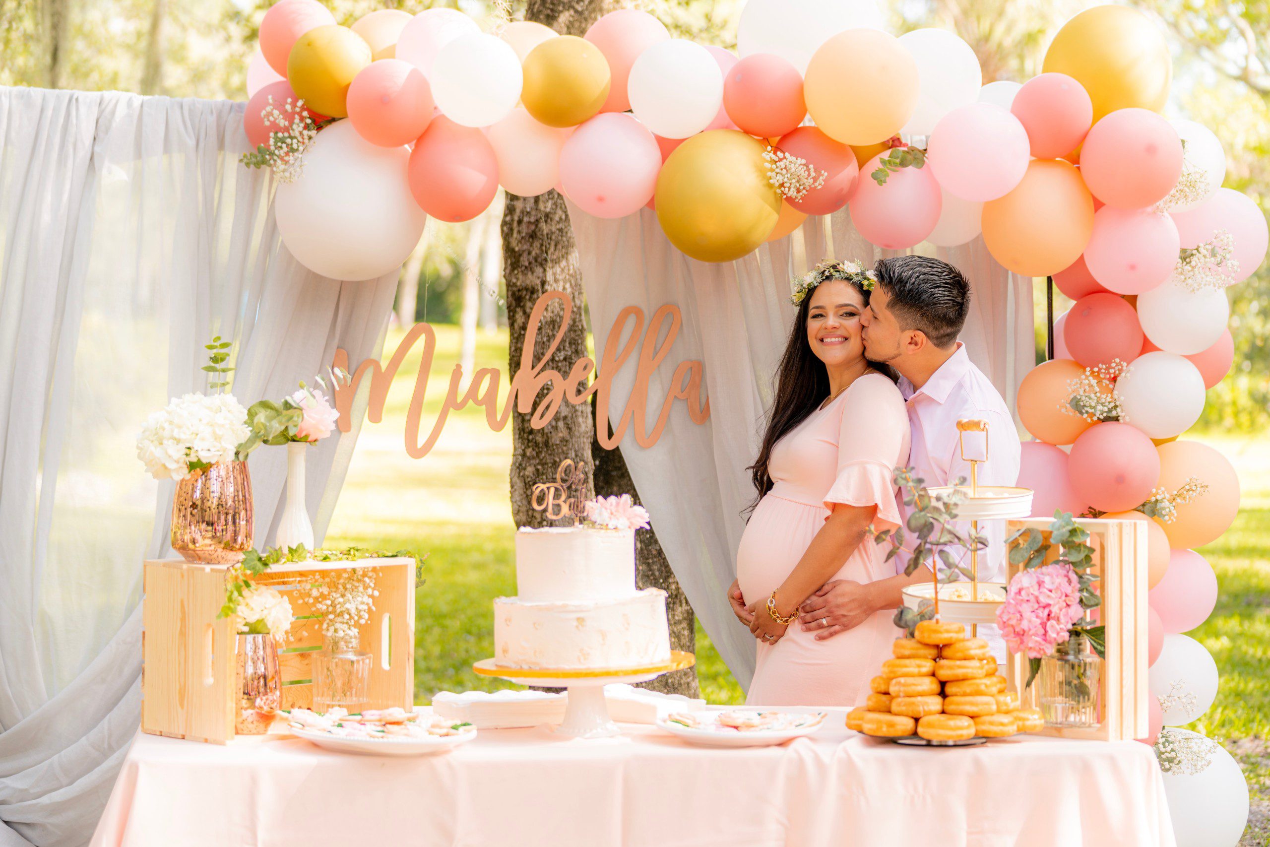 Imagem de uma mesa de doces em uma chá de fralda com um casal se abraçando.  