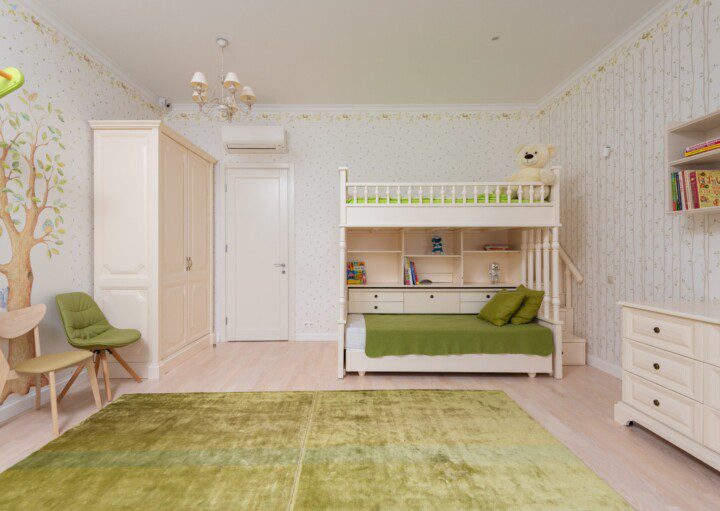 A foto mostra um exemplo de quarto infantil retrô. Com tons de verde e bege, o quarto é composto por um tapete, duas cadeiras, um beliche, uma cômoda e um guarda-roupas. Todos com design retrô.